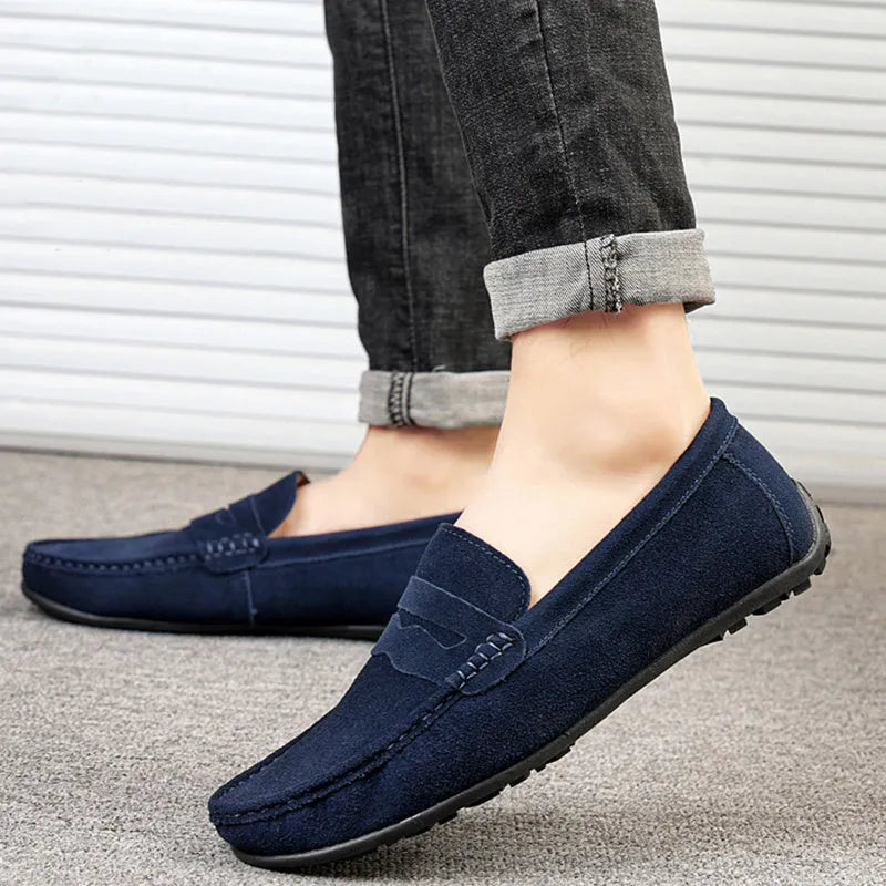 Men's brown suede slip-on loafers with round toe and flat rubber sole on a white background