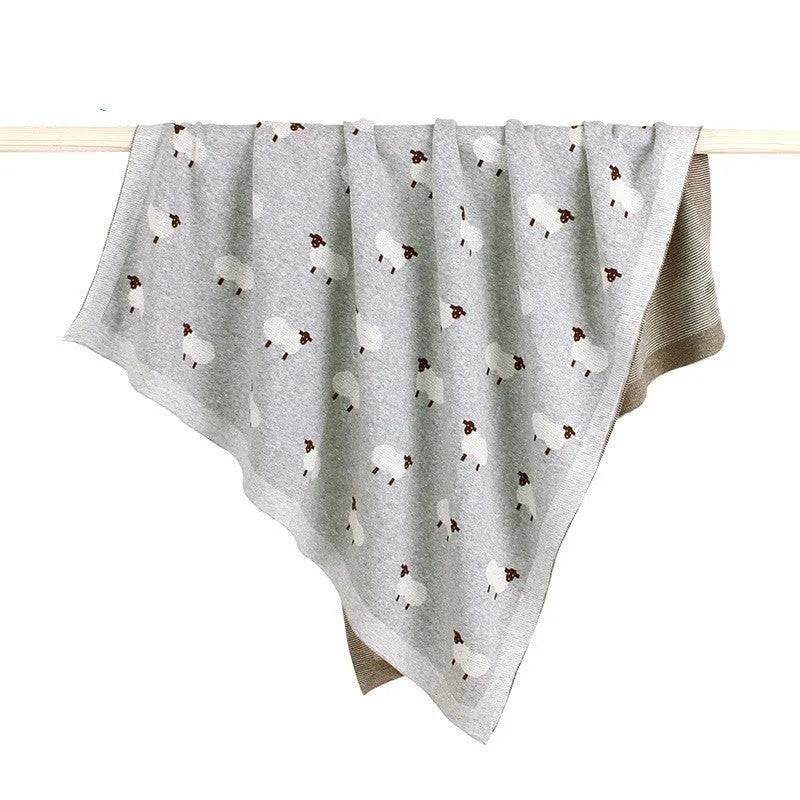 Grey and pink baby sheepskin blanket measuring 100cm by 80cm on a crib