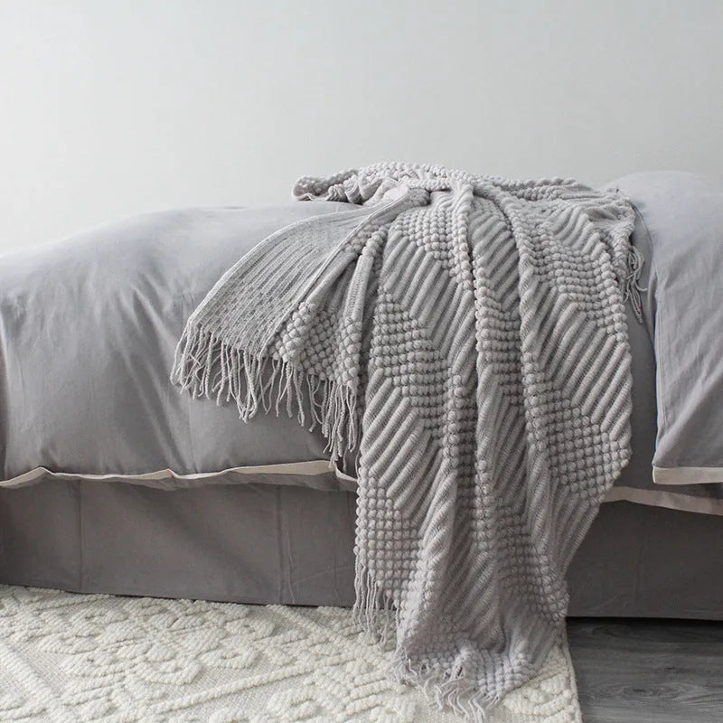 Small grey polyester nap blanket folded, showing its 127x170 cm size on a sofa.