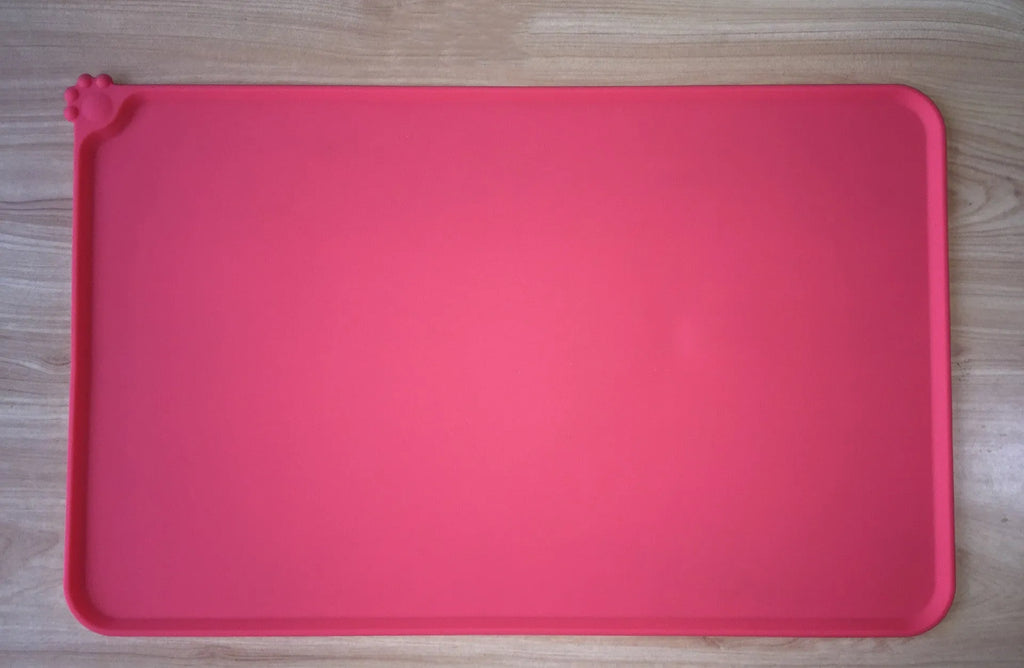 Black silicone dog food mat measuring 47 by 30 centimetres with non-slip surface and raised edges.