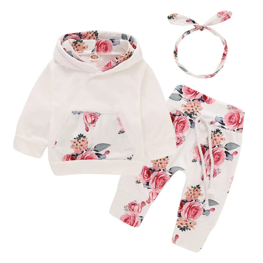 White cotton hooded tracksuit romper for a baby girl, showing long sleeves and full-length trousers.