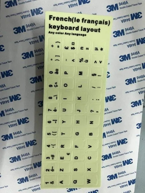 Yellow PVC sheet of glow-in-the-dark keyboard stickers for Arabic, Thai, Hebrew, French, Italian, and German layouts.