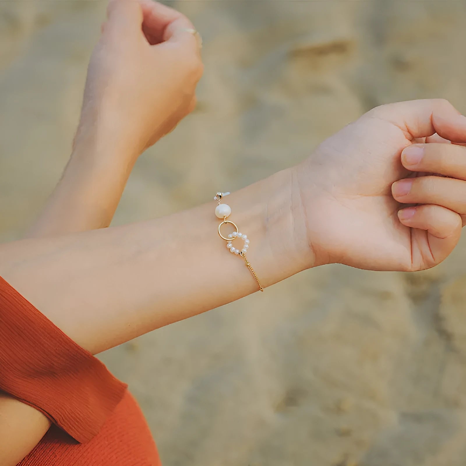 Women's natural pearl and gold-plated chain bracelet on a white background.