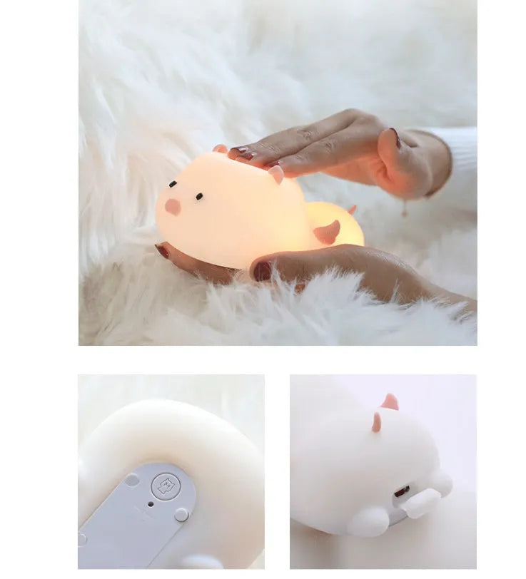 Blue rechargeable pig-shaped silicone night light with a sleeping design on a bedside table.