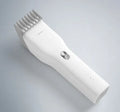 Black cordless hair clipper with a sliding length adjustment comb on a white background.