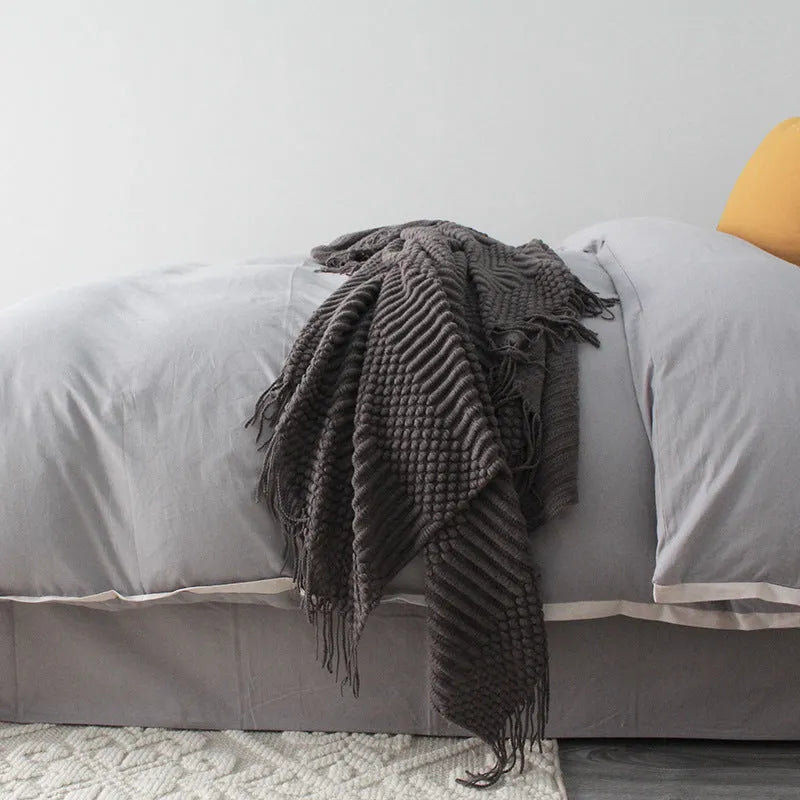 Small grey polyester nap blanket folded, showing its 127x170 cm size on a sofa.
