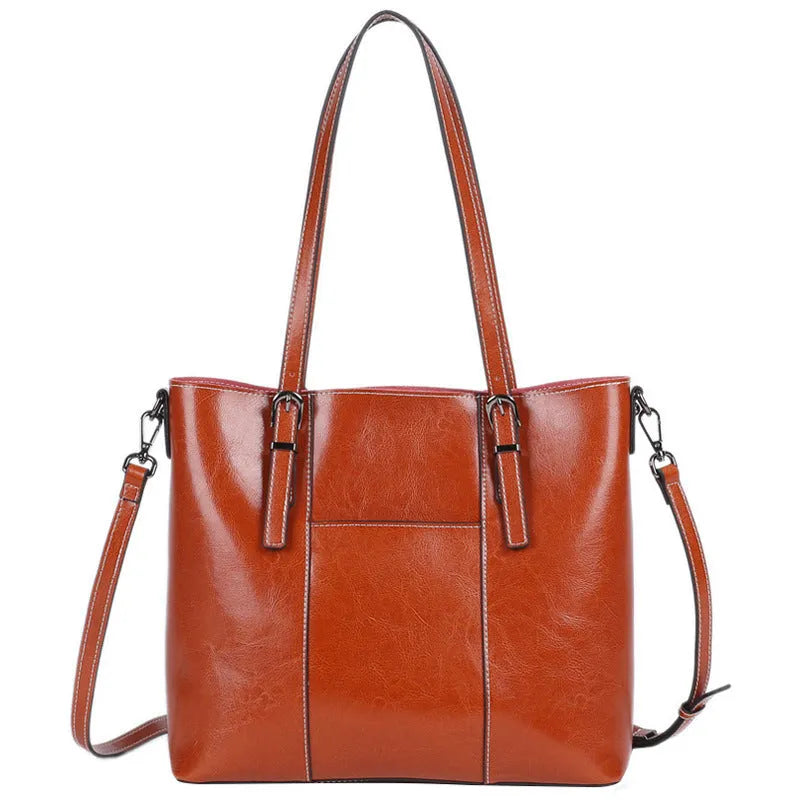 Brown genuine leather retro women's shoulder tote bag with three straps on a table.