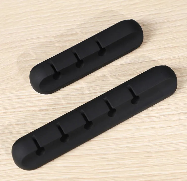 Black organic silicone desktop cable manager clips holding USB cables on a desk