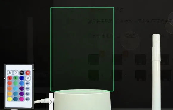 Black 3D acrylic message board lamp with remote control and marker pen on a desk.