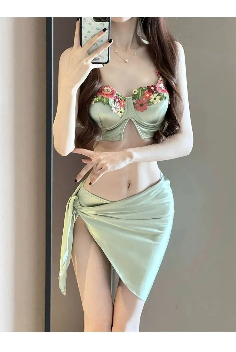 Green women's three-piece bikini swimsuit set with triangle top, briefs, and matching skirt