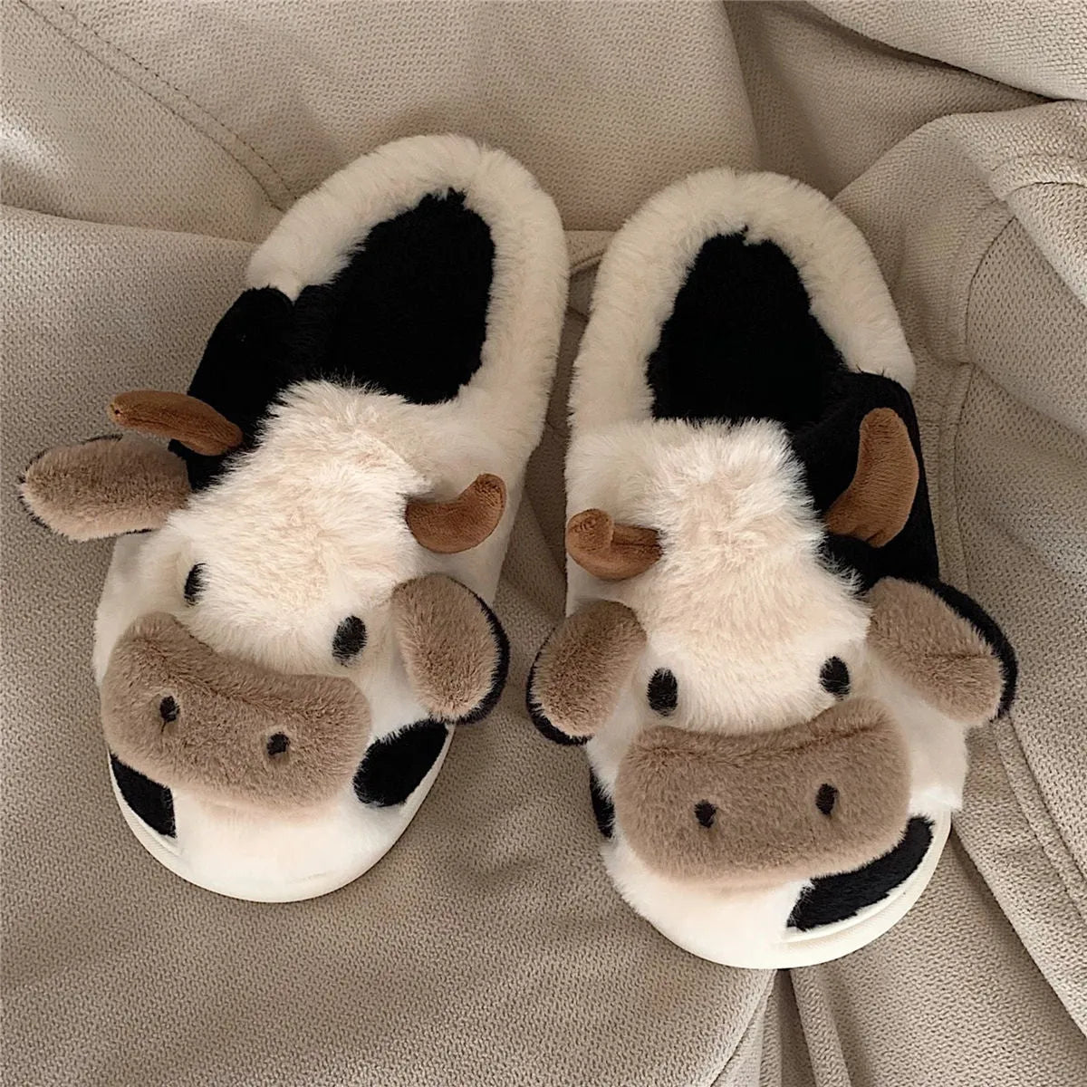 White and coffee cartoon cow slippers for women with plush faux fur and a textured non-slip sole.
