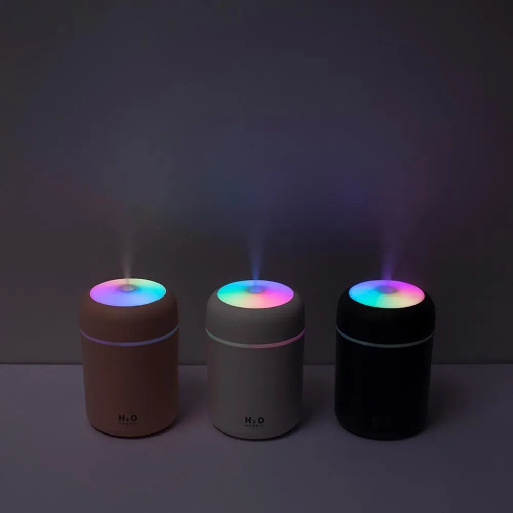 Pink USB desktop humidifier with 300ml water tank and colourful LED lights on wooden desk
