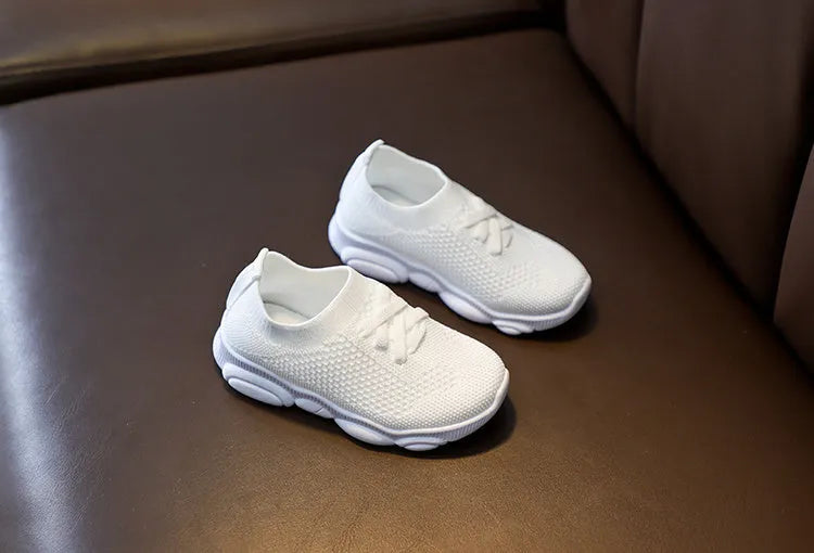 Children's white fabric lazy shoe with a non-slip rubber sole, shown on a foot.