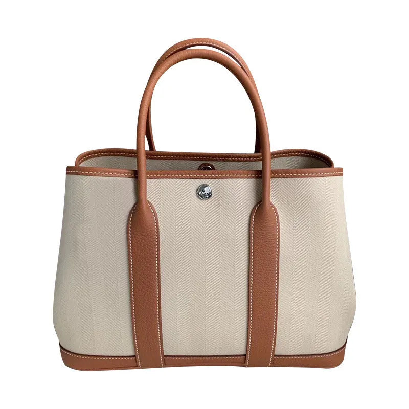 Women's canvas bucket tote bag with leather trim in black, shown with internal zip and document pockets.