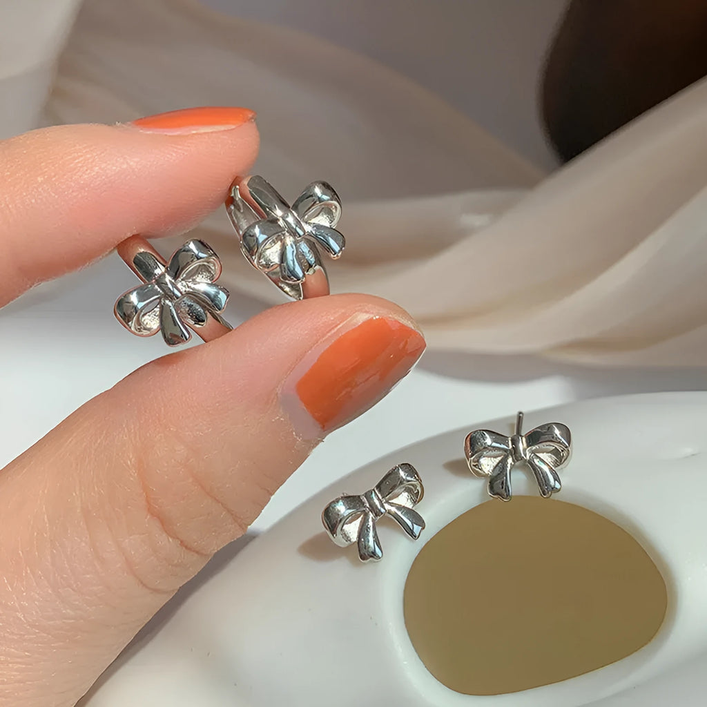 A pair of 925 sterling silver bow earrings in silver colour with electroplating finish on a plain background