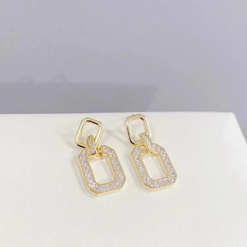 Pair of geometric alloy ear studs with electroplated finish on white background