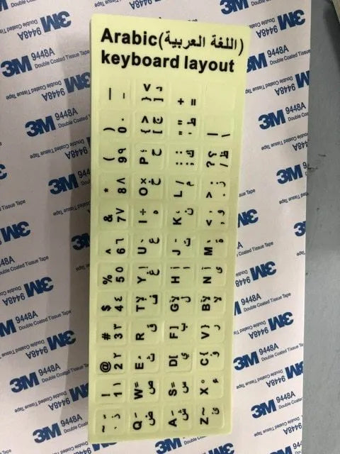 Yellow PVC sheet of glow-in-the-dark keyboard stickers for Arabic, Thai, Hebrew, French, Italian, and German layouts.