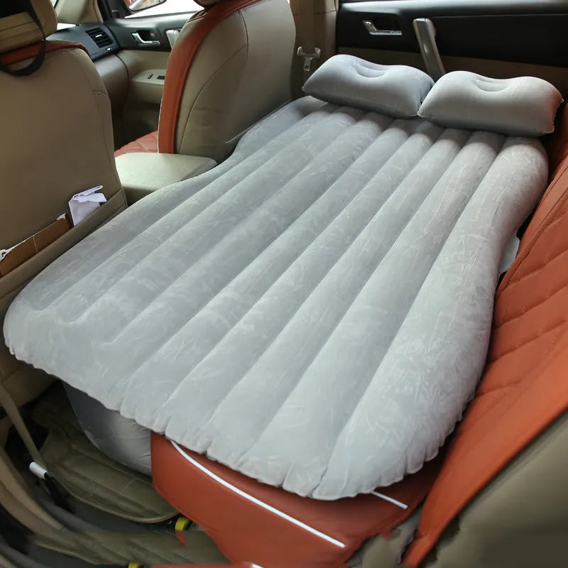 Inflatable car bed with flocking material shown in black colour, folded beside pillows and storage bag