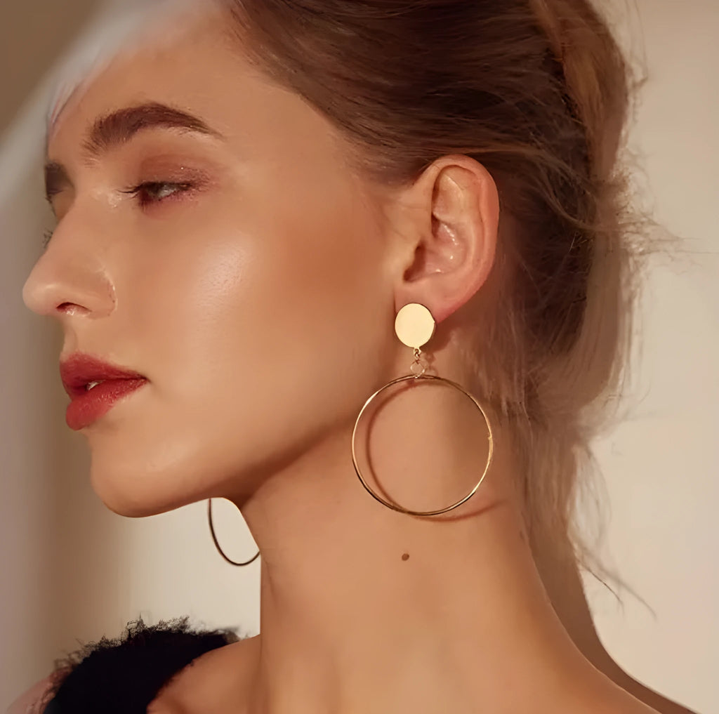 Large circle gold alloy hoop earrings with diamond-cut finish on white background