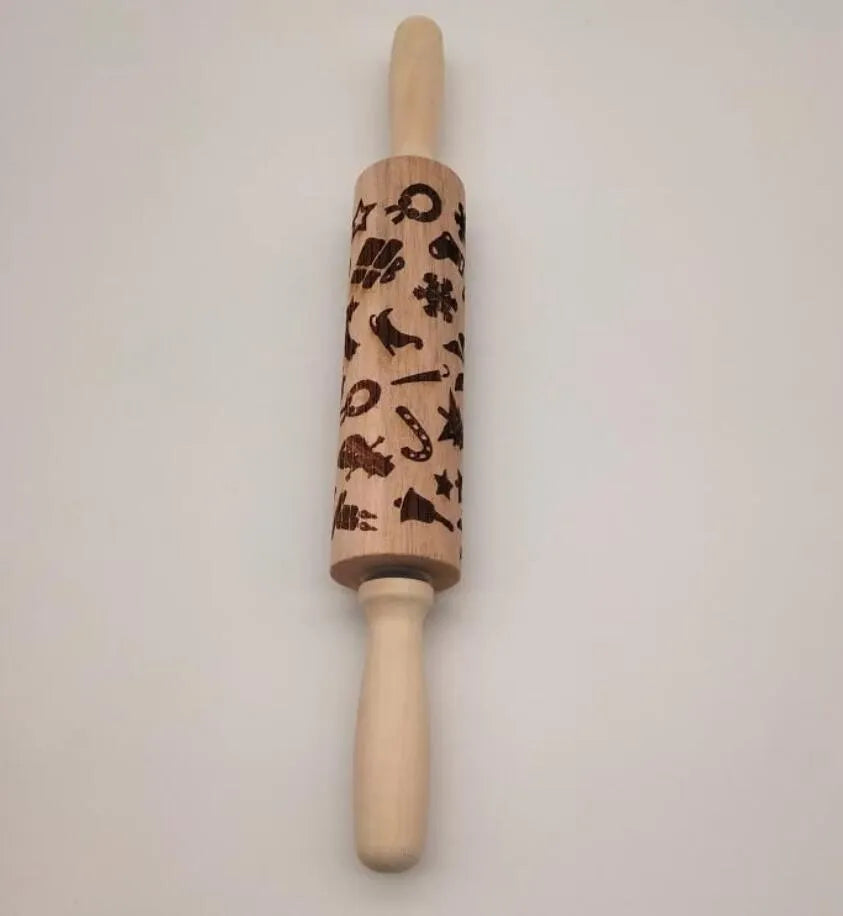 Wooden rolling pin with embossed Christmas patterns, 45cm long, on a kitchen worktop.