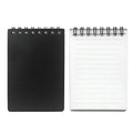 Spiral-bound black business notepad with pen and cleaning rag on a desk.