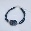 Obsidian bracelet with a hand-carved climbing cat charm on a dark background.