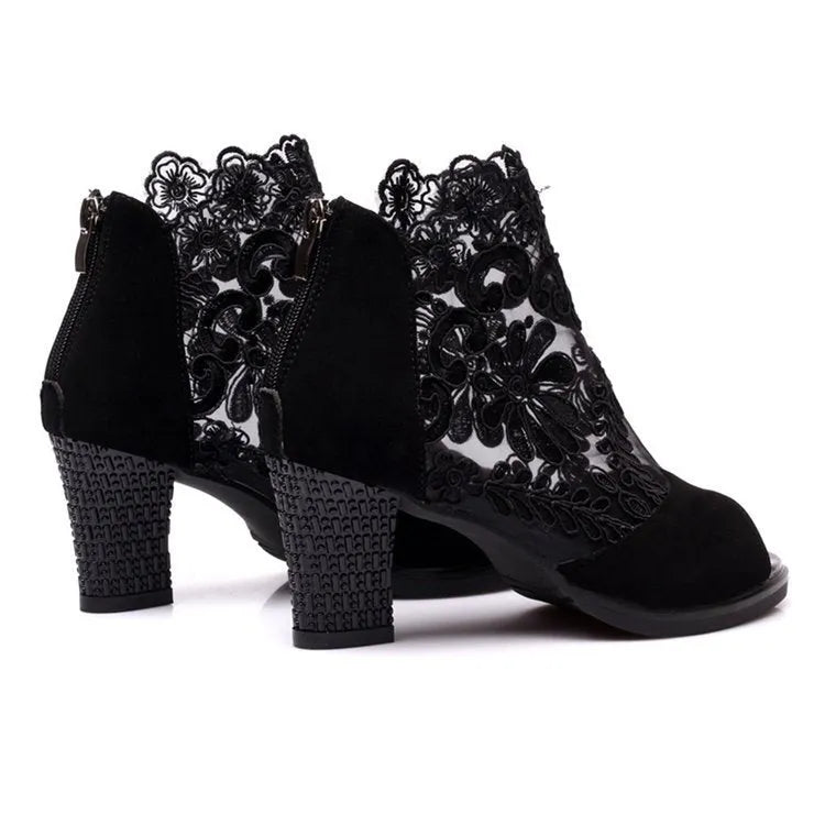 Black lace gladiator sandals with a square high heel, zip closure, and peep toe on a woman's foot