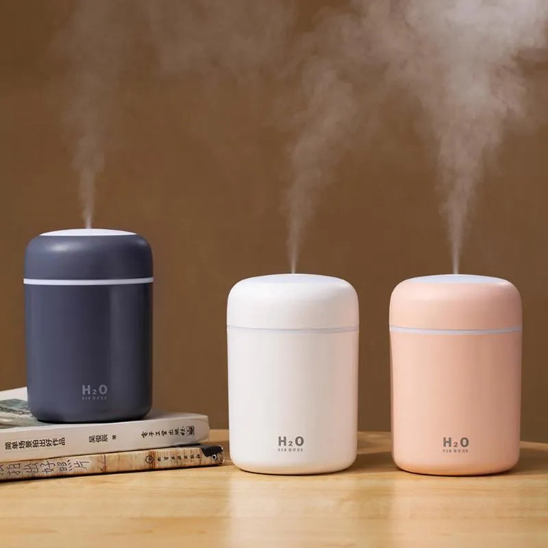 Pink USB mini humidifier with colourful lights on wooden desk