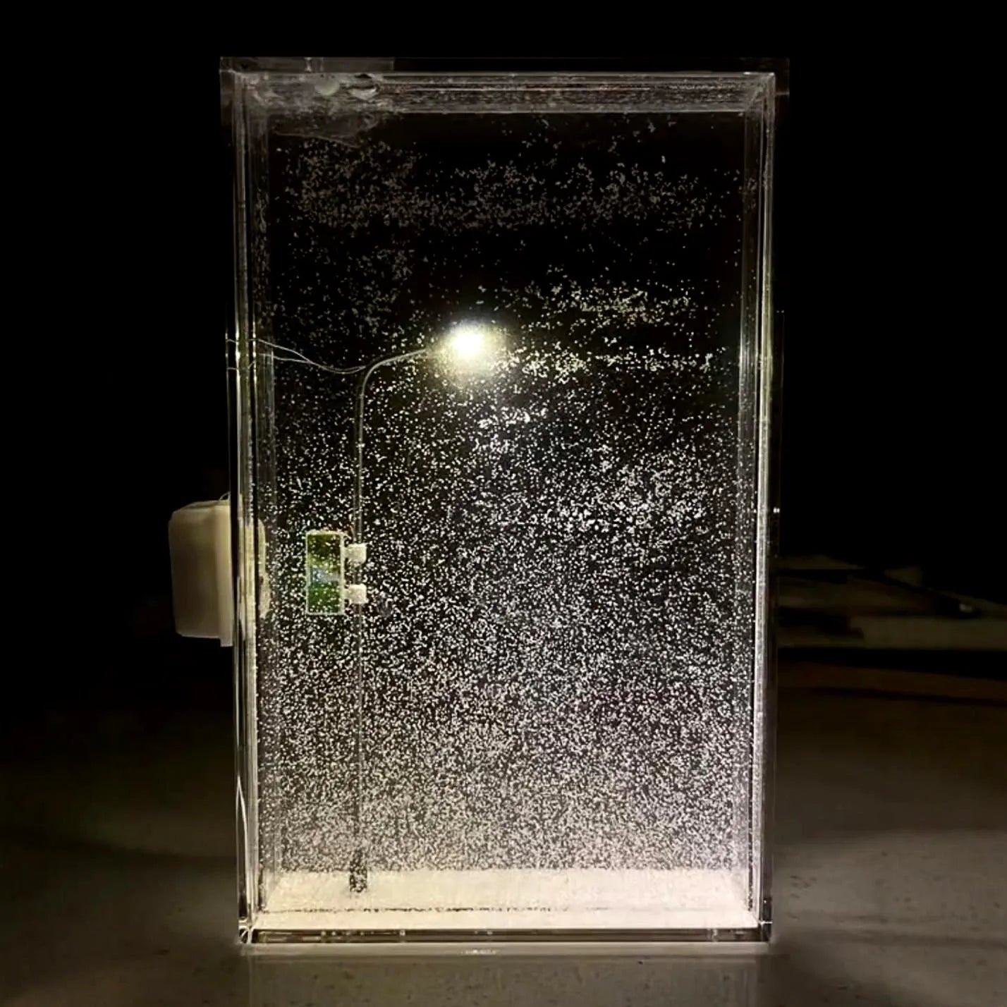 DIY material kit for building a snowy landscape night light with flowing snow effect and warm LED lights.