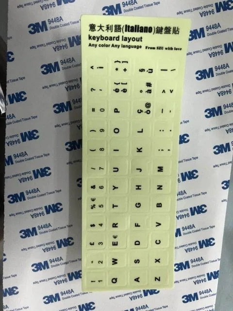 Yellow PVC sheet of glow-in-the-dark keyboard stickers for Arabic, Thai, Hebrew, French, Italian, and German layouts.