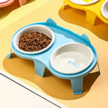 Blue ceramic cat food and water bowls in a white elevated plastic stand with a hook.