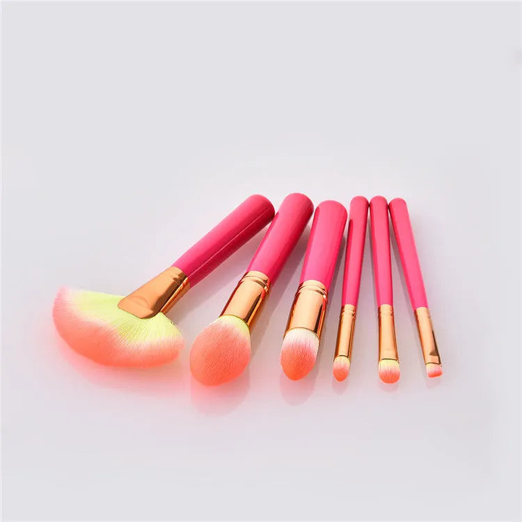 Pink cosmetic makeup brush set with wooden handles and synthetic bristles laid out on a surface