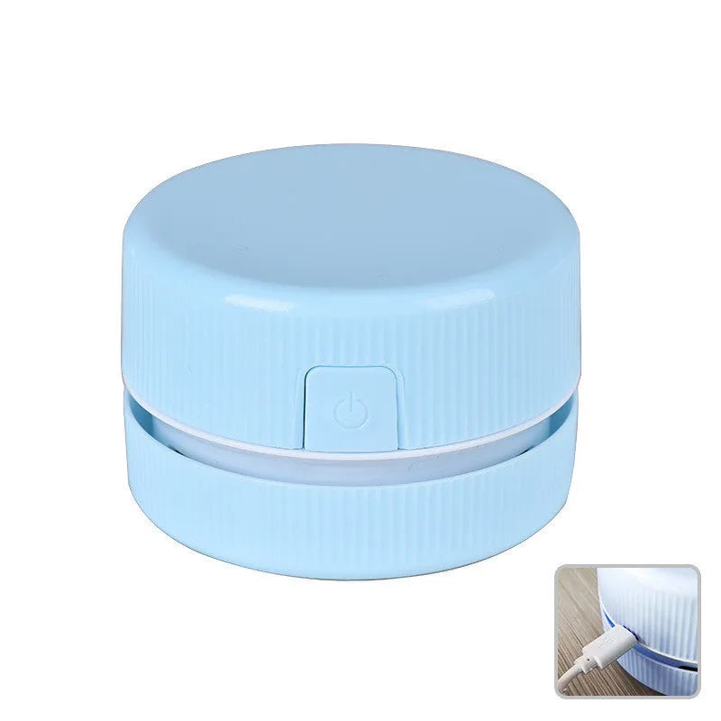 Blue rechargeable mini handheld desktop vacuum cleaner on a wooden desk next to pencils