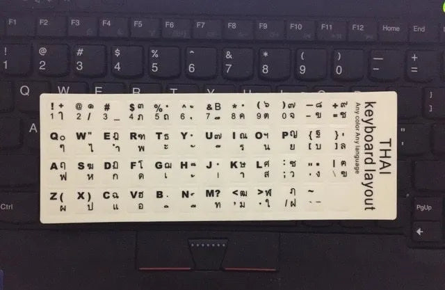 Yellow PVC sheet of glow-in-the-dark keyboard stickers for Arabic, Thai, Hebrew, French, Italian, and German layouts.