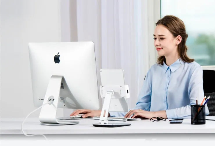 Silver foldable aluminium and ABS phone and tablet stand on a desk, showing 360-degree rotation.