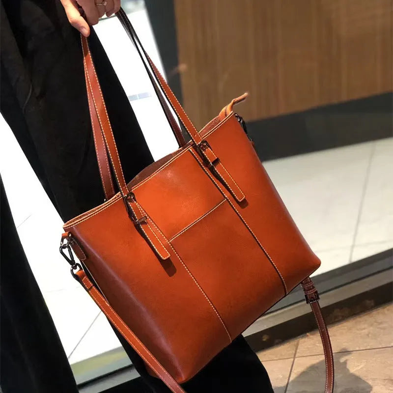 Brown genuine leather retro women's shoulder tote bag with three straps on a table.