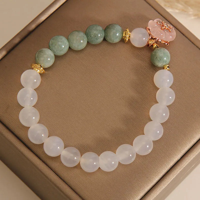Women's white agate jade bracelet with flower design and pink accents on adjustable sliding knot closure
