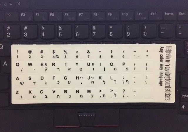 Yellow PVC sheet of glow-in-the-dark keyboard stickers for Arabic, Thai, Hebrew, French, Italian, and German layouts.