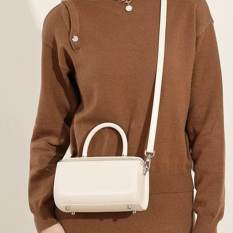 Brown leather women's crossbody bag with a single shoulder strap and clamshell opening.