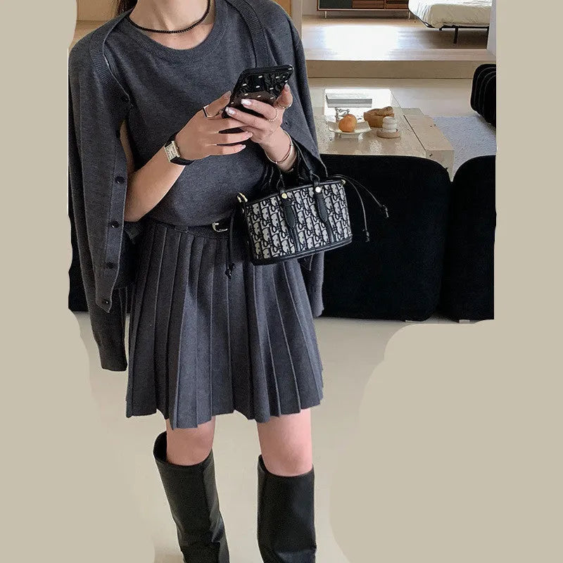 Women's black knitted vest skirt and long-sleeved cardigan two-piece set with pleats and a belt.