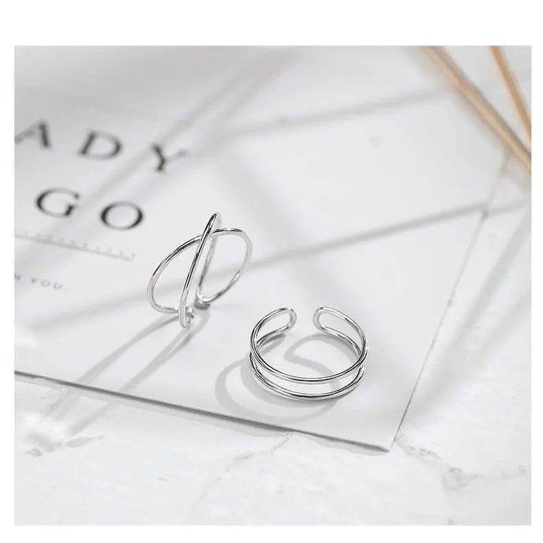 Silver-plated geometric cross ring with an adjustable opening on a copper base.