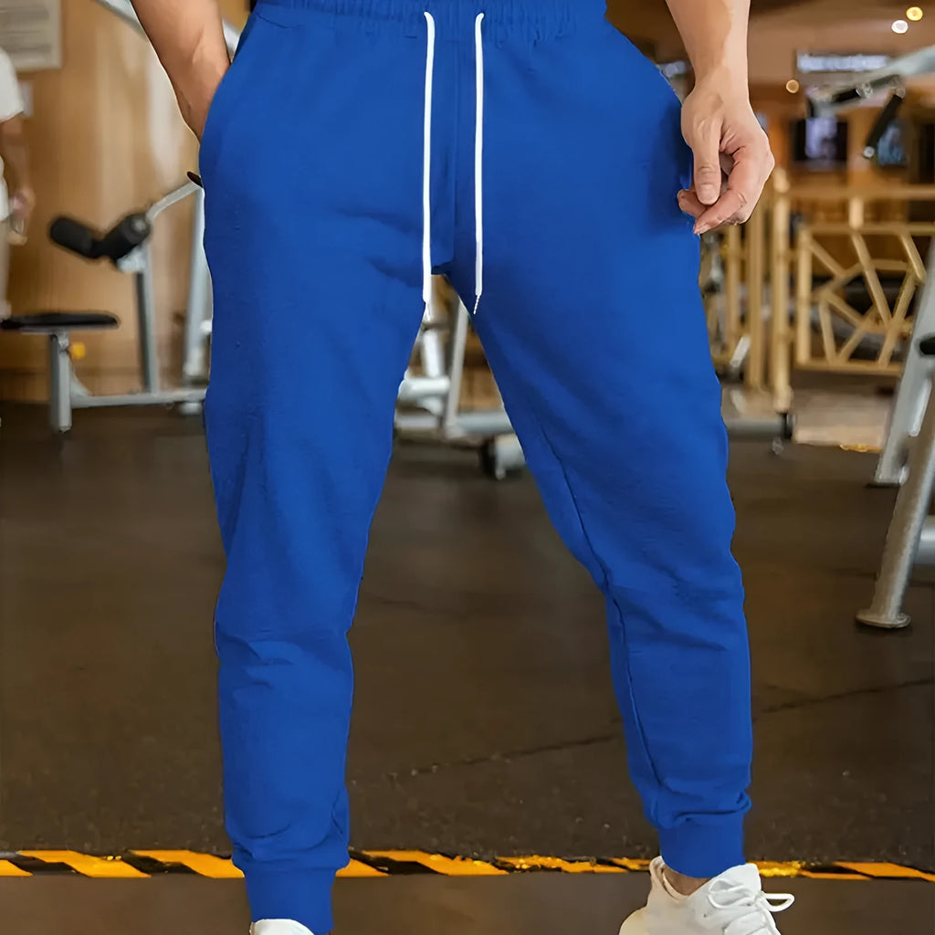 Man wearing beige linen-style loose fit trousers with an elastic drawstring waist.