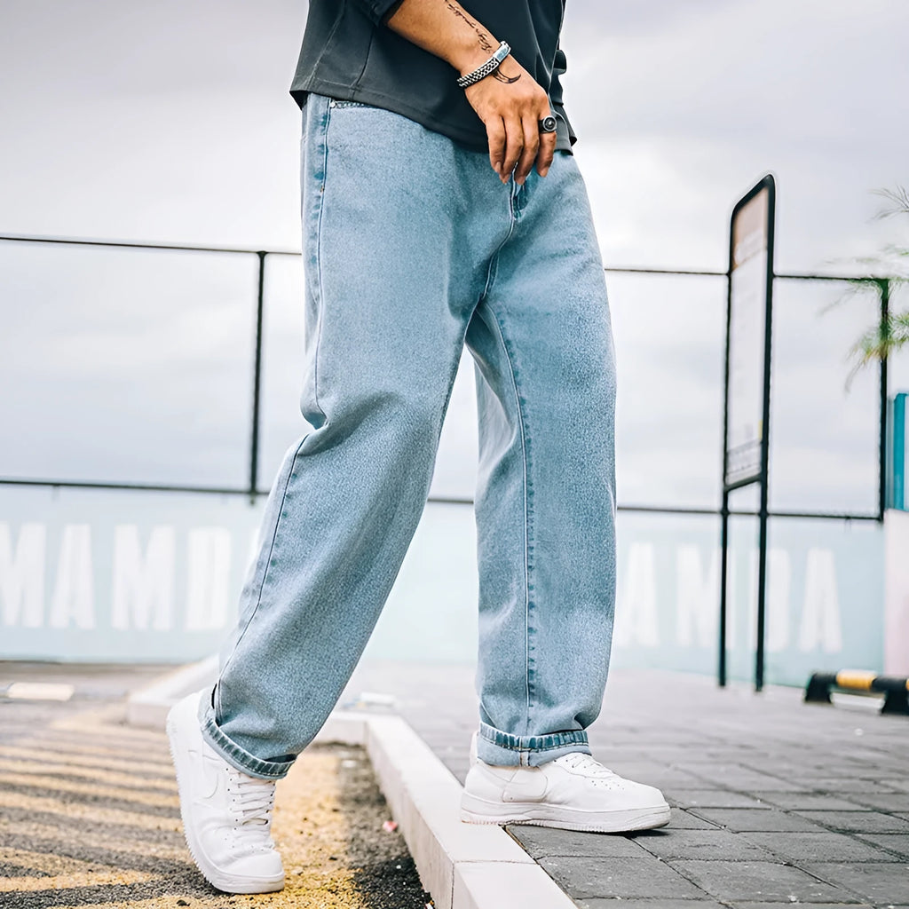 Men's loose straight-cut cotton jeans in dark blue, shown in a casual setting