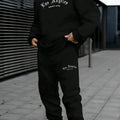 Men's grey hooded pullover sweater and matching trousers set on a hanger.