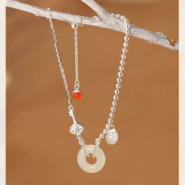 Women's silver bracelet with a geometric Hetian jade peace buckle charm on a chain.