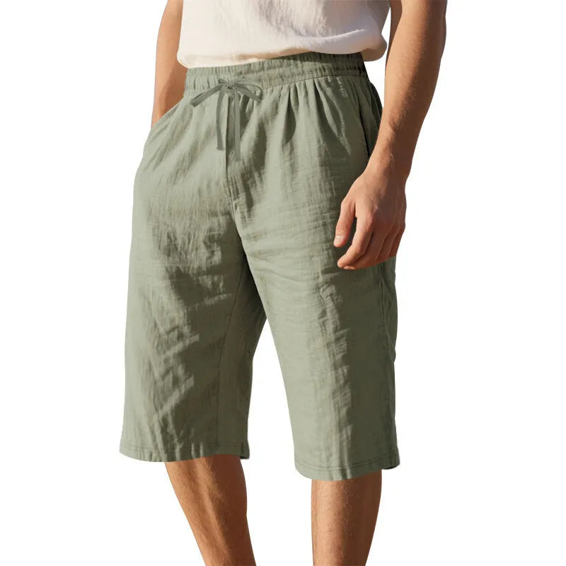 Men's loose linen shorts in light blue with drawstring waist and cropped length on white background