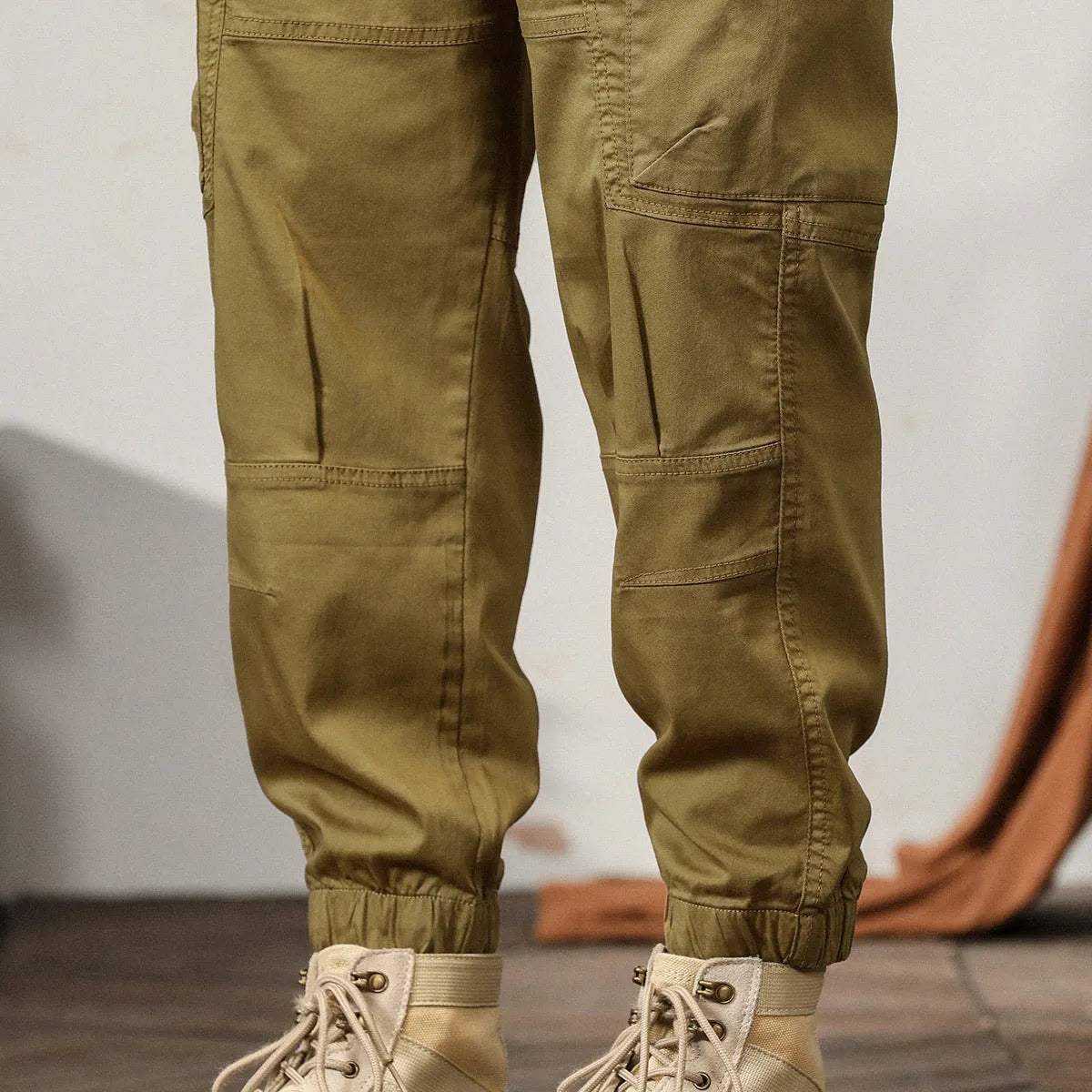 Men's khaki cotton harem pants with tapered ankle cuffs and a loose fit, shown laid flat.