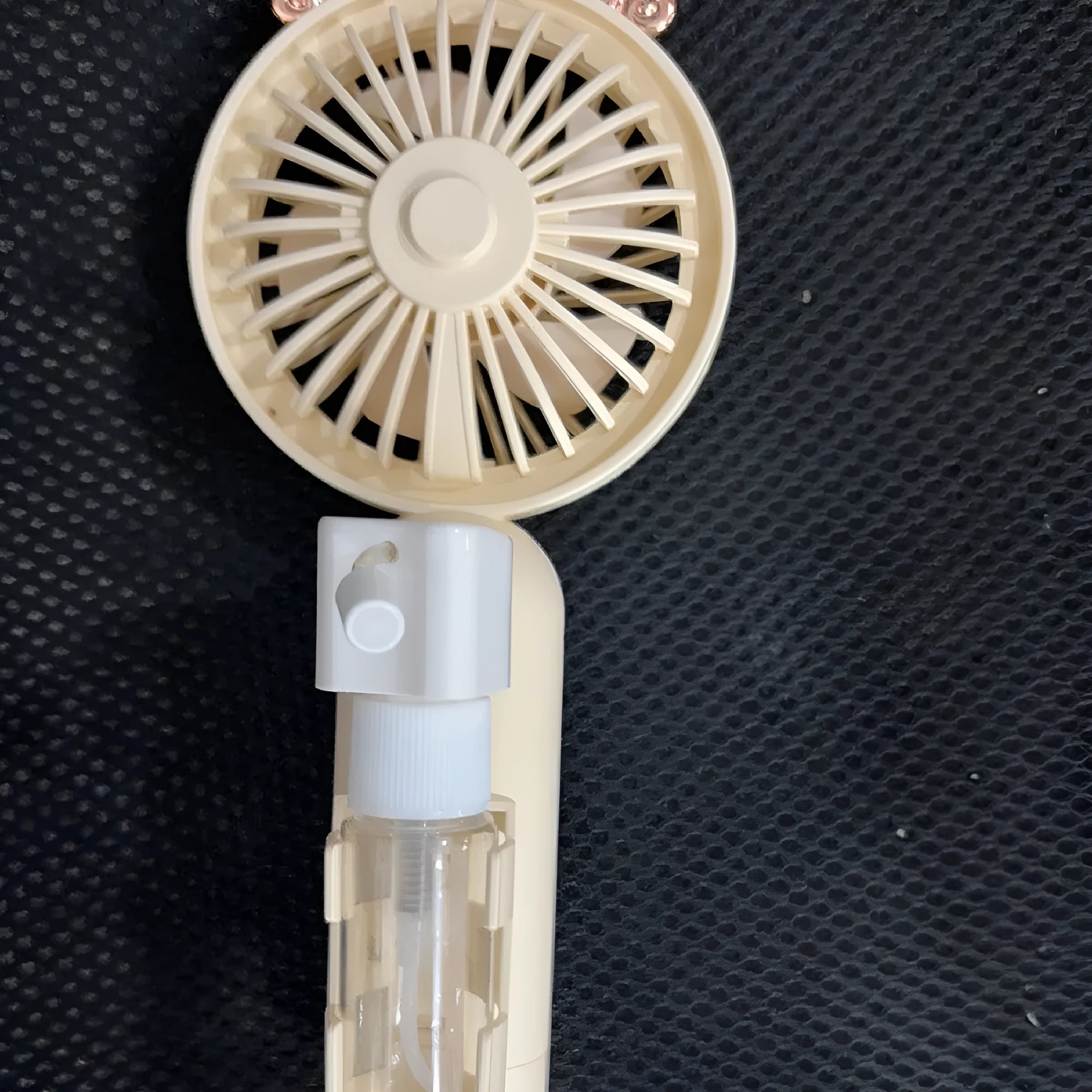USB rechargeable handheld plastic nozzle fan in apricot colour showing three speed buttons.