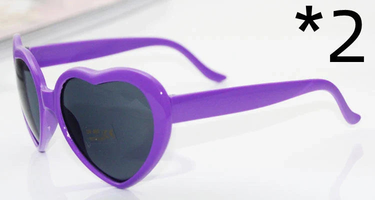 Heart-shaped glow-in-the-dark sunglasses in various vibrant colors, featuring a durable plastic frame and resin lenses for reliable UV protection.