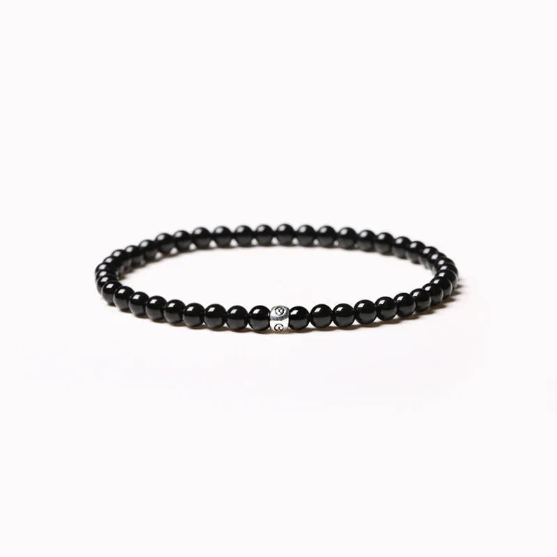 Simple geometric agate bracelet with round and square 4mm beads on a wrist.